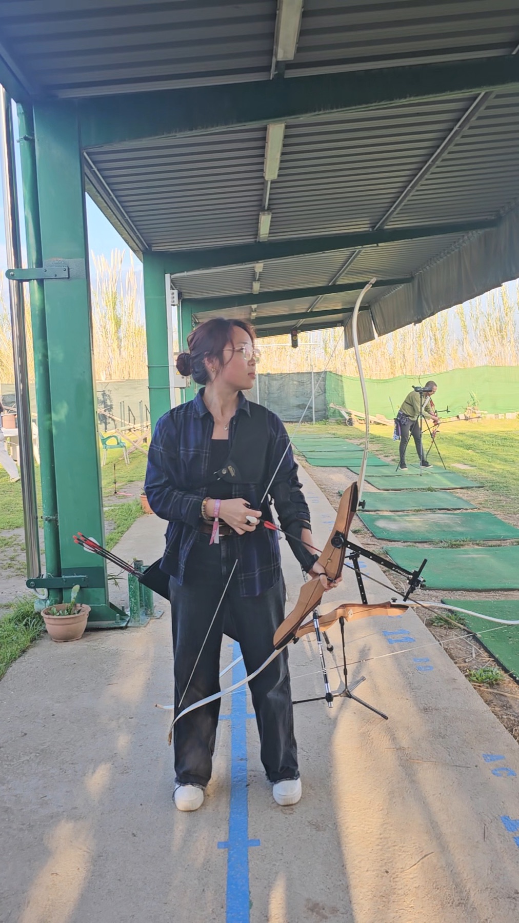 Tianyu holding a bow at an archery range